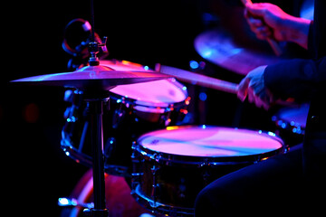 Naklejka premium Jazz rock music day Drummer playing drum kit with pink and blue stage lights image