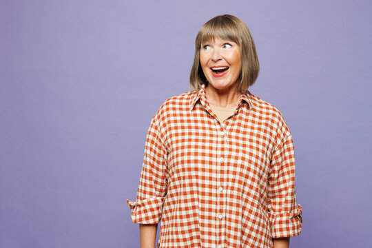 Smiling happy elderly gray-haired woman 50s years old she wearing casual clothes posing look aside on workspace area isolated on pastel plain pastel light purple color wall background studio portrait.