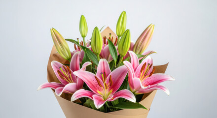 Obraz premium Pink lilies bouquet wrapped in brown paper with green buds, set against a light gray background for floral arrangements and gifting