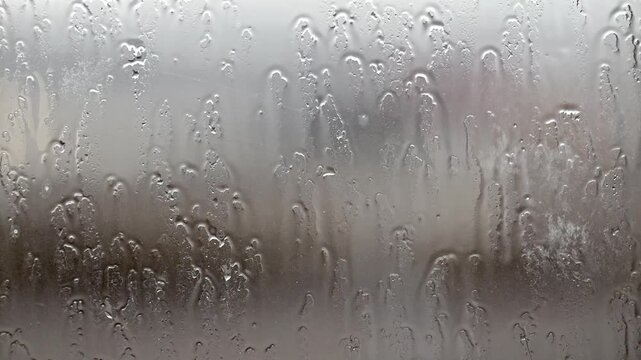 Raindrops cling to glass, blurring outdoor scenes. Water beads flow downward, creating soft, textured patterns. Hazy, muted tones evoke calm or melancholy feelings. Perfect for weather-themed projects