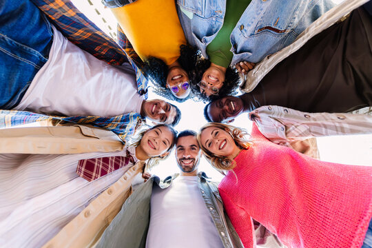 Smiling portrait of young college student friends in circle looking at camera. Youth community and diversity concept