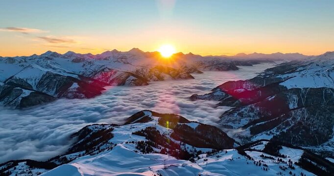 Golden sunrise light over snow-capped mountains and cloud inversion