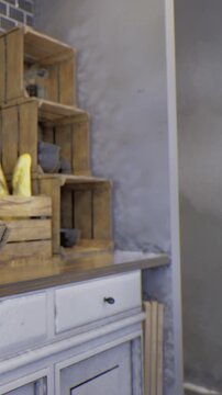 Wooden crates are stacked on a shelf, holding various items. A yellow object sits on the crate, adding color to the indoor space. The wall has a smooth appearance.