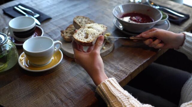 young beautiful woman spreads butter on bread in cafe, girl eats Ukrainian borscht with lard and bread in restaurant, close-up