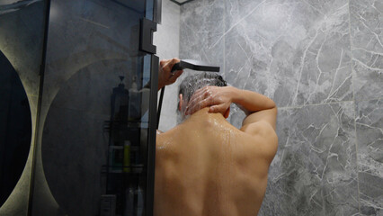 Man taking a shower in a modern bathroom with grey walls