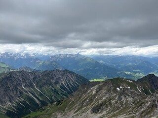 Obraz premium Spectacular panoramic view of alpine mountain ridges and a small summit station under a cloudy sky 