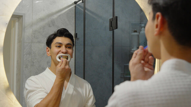 Man brushing his teeth in front of a mirror in the bathroom