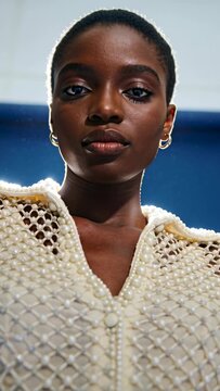 Vertical video: Model lifting chin while camera pulling up, showing pearl jacket for fashion