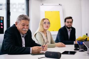 Obraz premium Business Executives Engaged in a Team Meeting Session Around a Bright Office Table