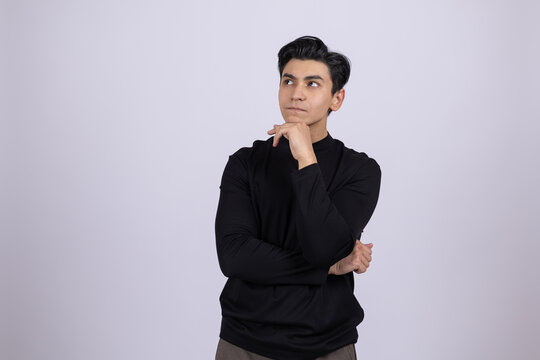 Thoughtful young man leaning on his hand in a studio setting