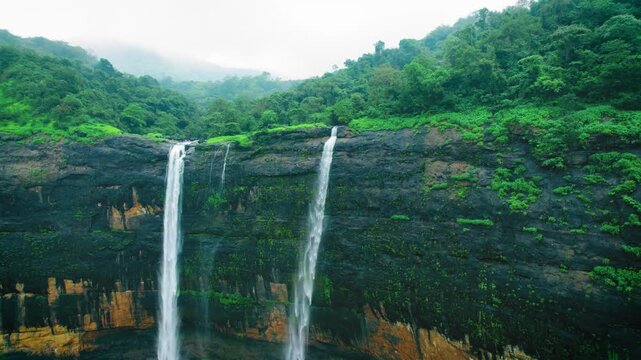 4K Aerial view of majestic Kataldhaar waterfall flowing from cliff during rainy day in Sahyadri Hills, Maharashtra, India. Green trees in forest hill and waterfall flowing in valley. Nature monsoon la