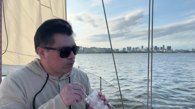 Man with sunglasses drinking refreshing beverage on boat in Rio de Janeiro Brazil