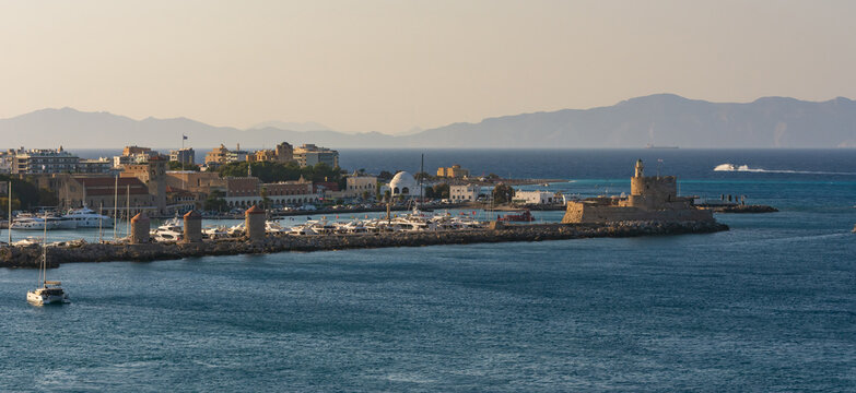 Panorama sereno del puerto de Mandraki en Rodas, Grecia, que muestra el Fuerte de San Nicol&aacute;s, los tres molinos de viento ic&oacute;nicos, el puerto deportivo lleno de yates