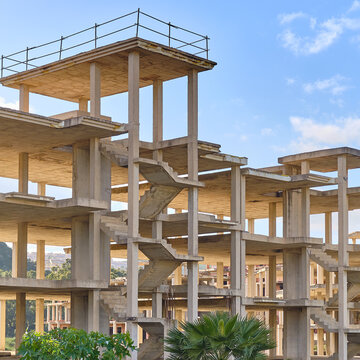 View of the stark, unfinished concrete skeleton of a building rises against the bright blue sky, promising future stories, Manilva, Andalusia, Spain.