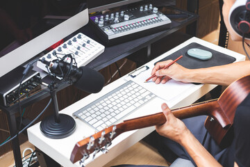 male musician writing a hit song by acoustic guitar in home studio