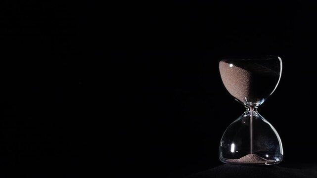 Hourglass flowing on black background. Right align comp with copy space on top and left, time management concept, minimalist product shot, hourglass in motion, clean style, starting to flow
