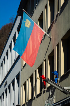 View of the vibrant blue and red flag of Liechtenstein waving proudly against the neutral facade of a building, Vaduz, Vaduz, Liechtenstein.