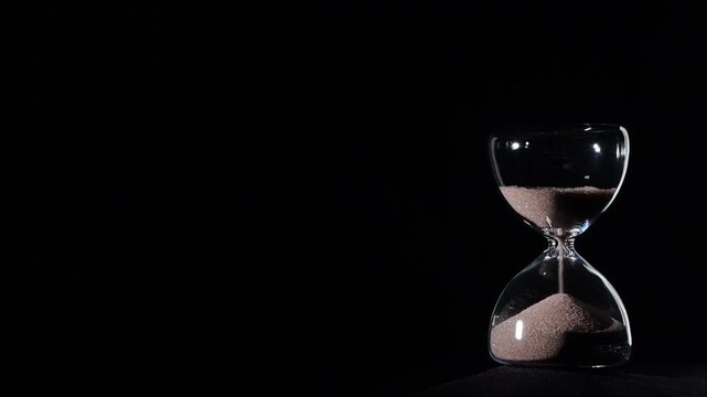 Hourglass flowing on black background. Right align comp with copy space on top and left, time management concept, minimalist product shot, hourglass in motion, clean style, last grains of sand
