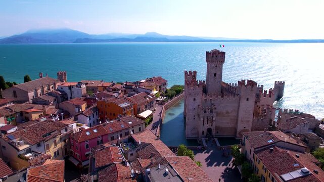 Italy Lake Garda Sirmione Aerial 4K Video Low Drone Flight Over Castle Canal with Ancient Walls and Cinematic Reveal to Empty Lake Water Surface Scenic Travel