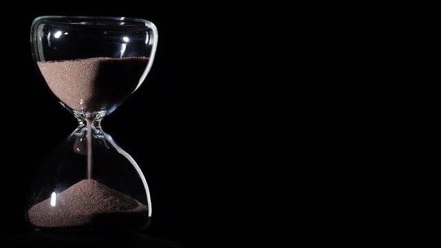 Hourglass flowing on black background. Left align composition with copy space on right, time management concept, minimalist product shot, hourglass in motion, clean style, approaching end