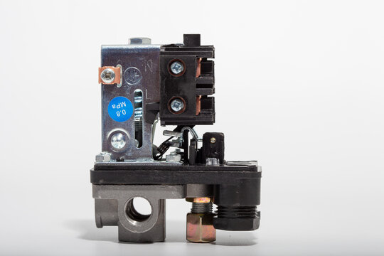 Top-down close-up of an air compressor pressure switch, showing the black plastic housing with technical specifications, a red round on-off power button, and a pressure regulator knob.