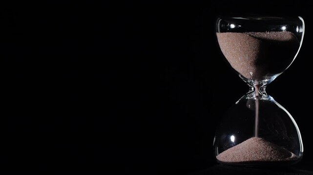 Hourglass flowing on black background. Right align composition with copy space on left, time management concept, minimalist product shot, hourglass in motion, clean style, steady flow
