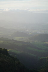 Fototapeta premium Rolling green hills with a wide valley view in warm sunlight. Peaceful and idyllic natural landscape