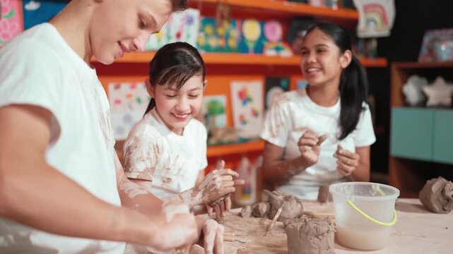 Caucasian high school girl modeling cup of clay while looking smart boy in art class at workshop. Multicultural student playing or making cup of clay art in creative activity. Education. Edification
