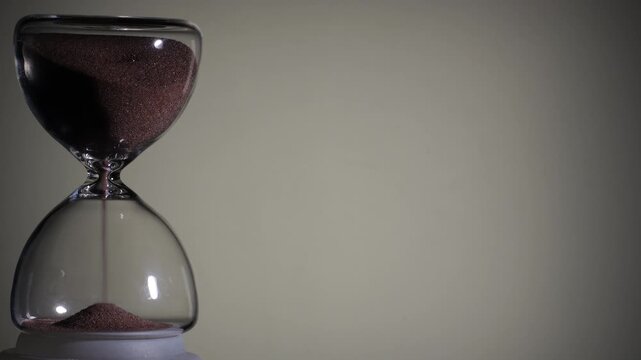 Hourglass flowing on white background. Left align composition with copy space on right, time management concept, minimalist product shot, hourglass in motion, clean style, starting to flow
