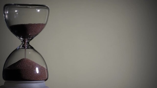 Hourglass flowing on white background. Left align composition with copy space on right, time management concept, minimalist product shot, hourglass in motion, clean style, last grains of sand
