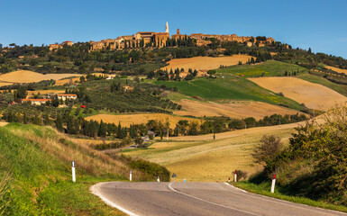 Naklejka premium Pienza townscape and winding road through Val d'Orcia landscape, Italy.