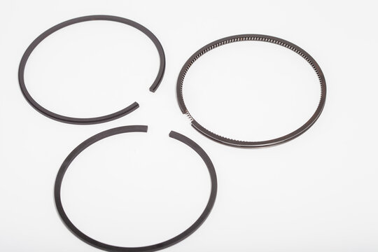 Set of new black engine piston rings with expansion spring for internal combustion engine overhaul, automotive maintenance, and mechanical repair services