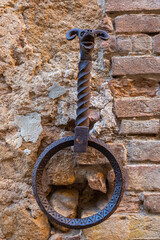 Naklejka premium Ornate iron hitching ring with animal head on ancient wall in Pienza, Italy.