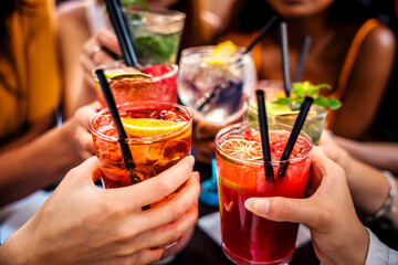 Happy people toasting cocktail glasses sitting at bar table - Cheerful friends enjoying happy hour at pub restaurant balcony - Food and beverage life style concept © Davide Angelini