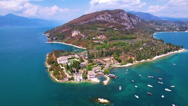 Punta San Vigilio 4k drone aerial view of Lago di Garda most romantic place in Italy. Scenic Garda lake panorama of historic village and Baia delle Sirene park in Veneto. Hidden gems of northern Italy