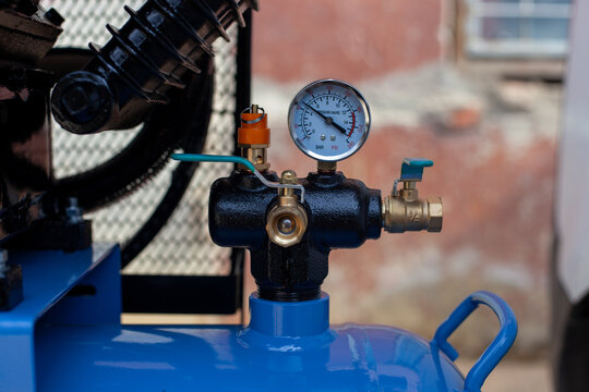 Top-down close-up of an air compressor pressure switch, showing the black plastic housing with technical specifications, a red round on-off power button, and a pressure regulator knob.