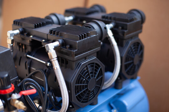 Oilless dual-piston air compressor motor block with cooling fans and braided hoses mounted on a blue tank for dental, medical, and quiet industrial clean air applications.