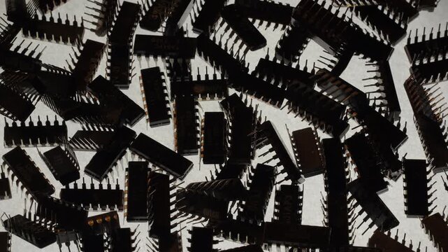 Top down macro of rotating TTL integrated circuit chips pile. Professional dual lighting with cold back backlit and misty low warm key lights, semiconductor components