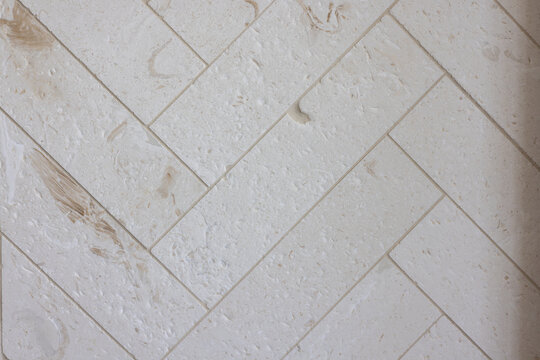 White herringbone stone tile pattern with natural texture close up