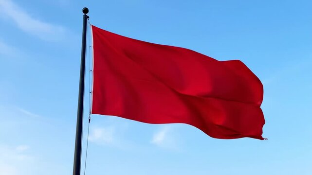 Red flag waving against a clear blue sky, warning concept