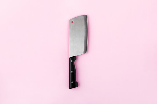 Stainless steel cleaver knife with black handle isolated on pastel pink background. Minimalist kitchen utensil image for culinary, food, or restaurant concepts.