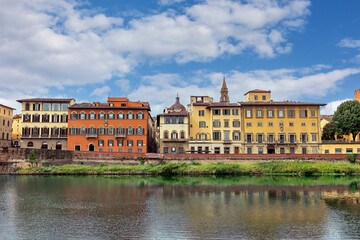 Fototapeta premium This scene highlights the Arno River along the Lungarno Torrigiani in Florence. Colorful buildings reflect in the water while the historic Palazzo Bardi-Guicciardini stands nearby.