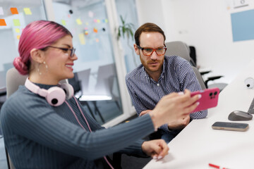 Fototapeta premium Businesspeople collaborate on a smartphone during a meeting in a modern office space with casual decor and bright colors