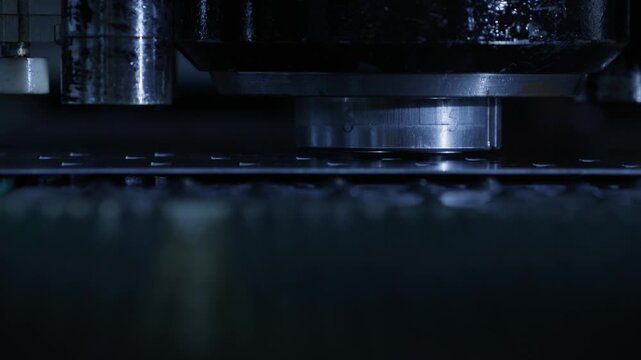 Slow motion metal press punching sheet metal on factory production line in workshop..