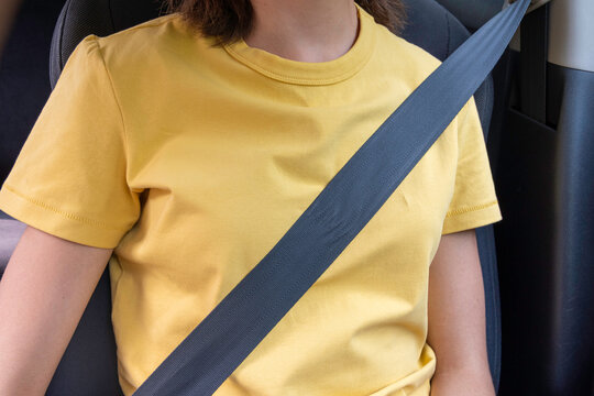 Person wearing yellow shirt seated in a car with a seatbelt fastened. safety of the driver and passenger. Safe driving. Caring for passengers