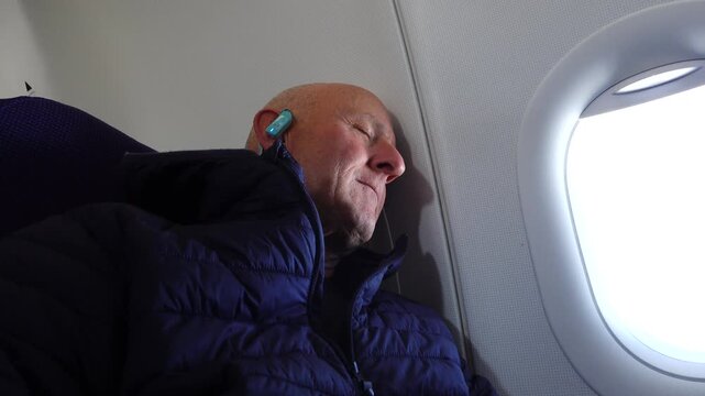 Stockholm, Sweden A man sleeping on a passenger airplane against the bulkhead,. 