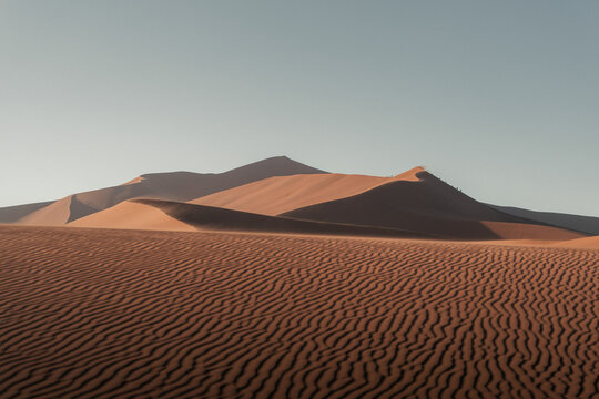 View of the undulating dunes cast long shadows, creating a mesmerizing dance of light and shadow on the sandy canvas, Namibia, Namibia.