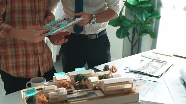 Smart architect or civil engineer writing building structure idea on note and stick on blueprint. Aerial view of manager working together with diverse colleague and show house plan. Alimentation.