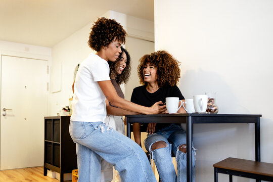 Three friends enjoying coffee and laughter at home