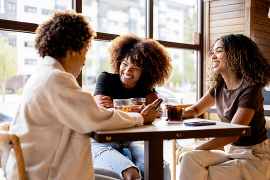 Friends enjoying a drink and laughing at a cafe table